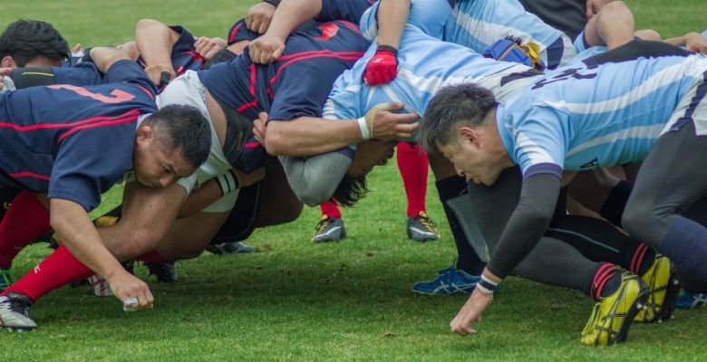 a group of rugby players on the pitch, in a scrum formation